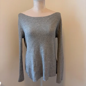 Grå off-shoulder tröja från Zara - Säljer en  grå off shoulder tröja från Zara med omlottdetalj i ryggen. Tröjan har en offshoulder-design och långa ärmar. 