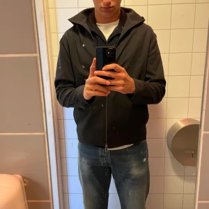 Svart jacka från J.Lindeberg - Snygg svart jacka från J.Lindeberg med dragkedja och huva. Perfekt för en stilren look. Nypris var 3000 men köpte på tabbar för 1500, för två år sedan, riktigt snygg tröja men blivit för liten nu