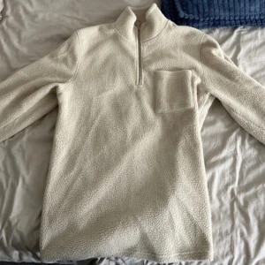 Beige fleece tröja med dragkedja - Säljer en supermysig beige ull fleece tröja som är perfekt för kyliga dagar. Den har en halv dragkedja framtill. Tröjan är långärmad och känns riktigt varm och skön. Perfekt för höst och vinter! Använd fåtal gånger.
