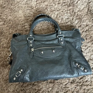 Balenciaga city bag - Balenciaga City bag i grått med silverdetaljer. Inköpt på TheRealReal förra året. Väldigt fint skick. Spegel medföljer men har defekter sedan innan. 