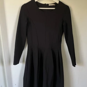 Svart klänning från Weekday - Säljer en elegant svart klänning från Weekday. Den har en klassisk design med långärmad stil och en dragkedja i ryggen. Perfekt för både vardag och festliga tillfällen!