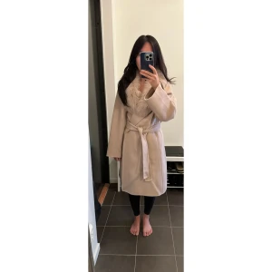 Beige kappa med fuskpäls - Populär beige Dennis Maglic kappa (alltid slutsåld) med fuskpälsdetaljer runt kragen. Köpte för 3000 kr och är i nyskick (oanvänd).