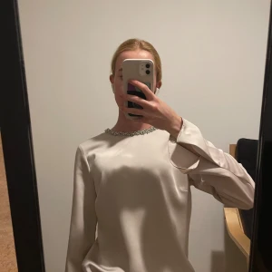 Blus med pärlor - Beige blus med silverpärlor kring halsen. Satinmaterial och i bra skick