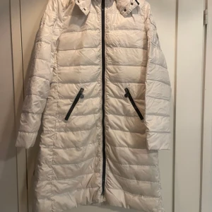 Moncler jacka  - Myynnissä Monclerin valkoinen kevytuntuvatakki. Polvipituinen, koko 4/M-L, irroitettava huppu. Pesty useamman kerron, koska valkoinen väri. Täysin ehjä.