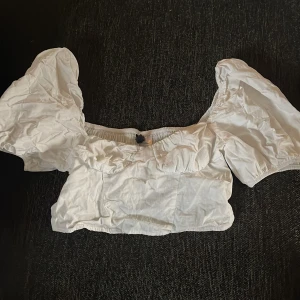 Vit blus med puffärmar - Säljer en söt vit blus med puffiga kortärmar och en elastisk detalj vid halsringningen. Perfekt för en somrig look!