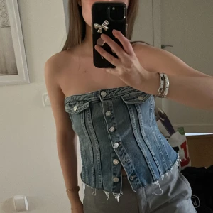 Jeans korsett - Trendig jeans korsett med knappar framtill. Axelbandslös design som ger en snygg och stilren look. 
