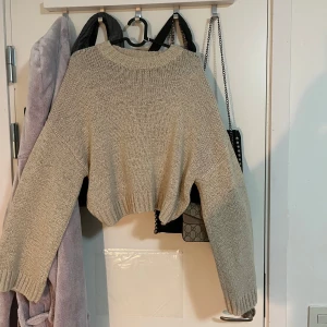 Beige stickad tröja från H&M - Säljer en mysig beige stickad tröja från H&M. Tröjan har en croppad design med långa ärmar och ribbade muddar. Perfekt för kyliga dagar!