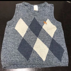 Grå stickad väst med diamantmönster - Snygg grå stickad väst med klassiskt diamantmönster i mörkgrått och vitt. Perfekt för att lägga till en touch av stil till din outfit.