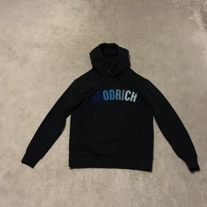 Svart hoodie från Hoodrich - Säljer en svart hoodie från Hoodrich med blå text på bröstet. Tröjan är använd 2 gånger och säljer den eftersom den är för liten. Mit pris: 200kr Ny pris: 650kr