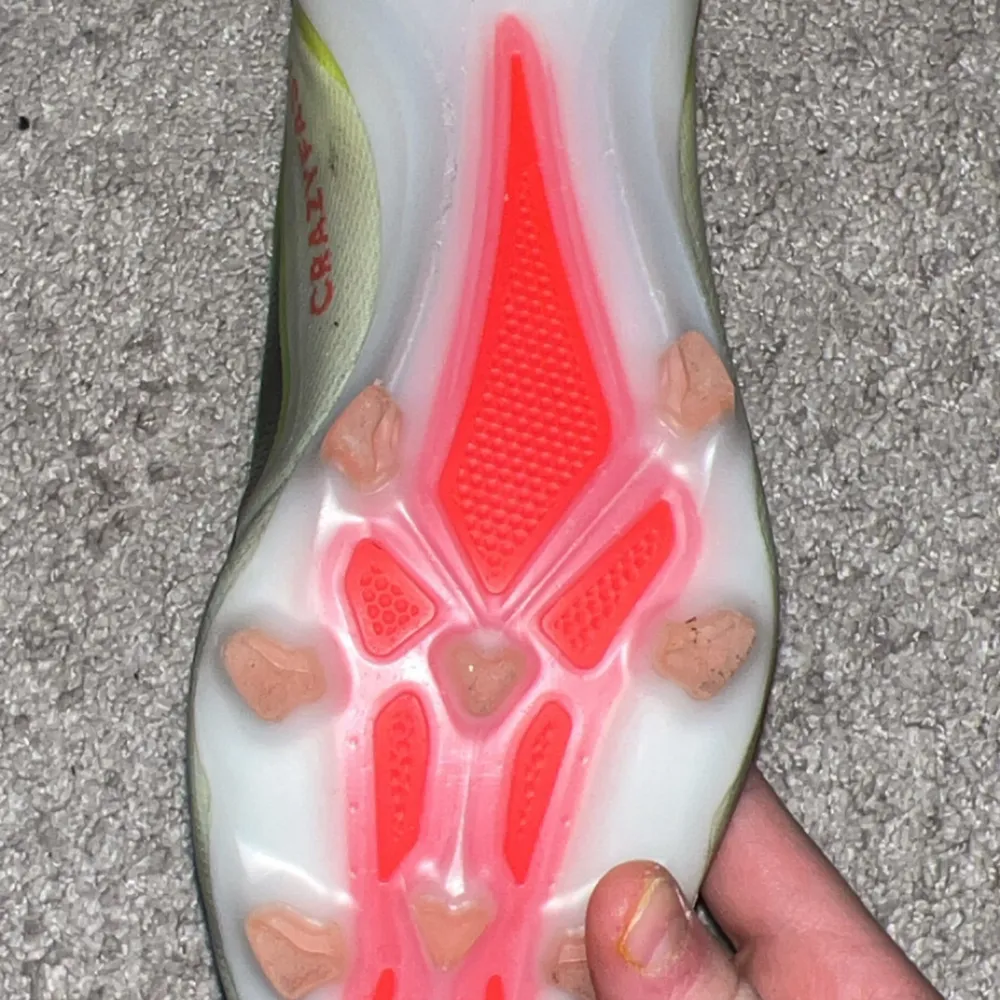 Säljer ett par gula fotbollsskor från Adidas med svarta detaljer och en neonorange sula. Skorna har en strömlinjeformad design utan snörning för en tight passform.. Kengät.