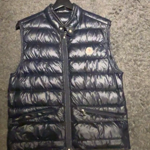 Moncler väst - Tja, säljer denna snygga moncler väst då den är för liten för mig, strl 2, det motsvarar M, äkta är den såklart. Skicka 9/10 ser ut som ny. Tveka inte att hör av dig vid funderingar😄