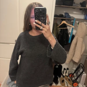 Mörkgrå stickad tröja från 157 - Säljer en mysig mörkgrå stickad tröja från lager 157. Tröjan har en enkel design med långa ärmar och rund halsringning. Perfekt för kyligare dagar.