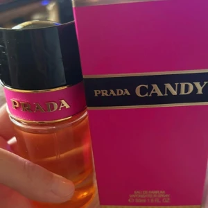 Prada Candy Eau de Parfum 50 ml - Prada Candy Eau de Parfum är en lyxig och söt doft med en distinkt rosa och svart flaska. Den har en elegant design med en gyllene vätska inuti. Perfekt för den som älskar en djärv och feminin doft. Ny, endast öppnad och testsprutad. Nypris 1400:-