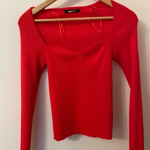 Röd ribbad topp från Gina Tricot - Snygg röd ribbad topp från Gina Tricot med långärmad design och en stilren v-ringning. Perfekt för att lägga till en färgklick i garderoben. Passar bra till både jeans och kjol.