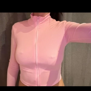 Rosa ribbad croppad tröja med dragkedja - Snygg rosa croppad tröja med dragkedja framtill. Tröjan är ribbad och har långa ärmar, perfekt för en trendig look.