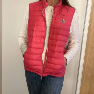 Rosa dunväst från North Sails - Snygg rosa dunväst från North Sails med dragkedja och logotyp på bröstet. Perfekt för kyliga dagar och lätt att matcha med olika outfits.