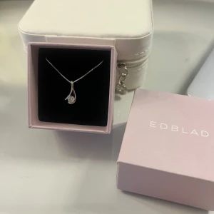 Silverhalsband med hänge från Edblad - Elegant silverhalsband från Edblad med ett stilrent hänge som har en gnistrande sten. Perfekt för att ge en touch av elegans till din outfit. Kedjan är tunn och smidig, vilket gör den bekväm att bära.