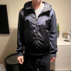 J Lindeberg jacka  - Snygg svart och blå jacka med huva och dragkedja. Perfekt för kyligare dagar och inför våren , använd men i super bra skick. Passar mig super som är 189, vid övriga frågor är det bara att höra av sig privat✌️