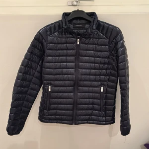 Marinblå dunjacka från Peak Performance - Snygg och funktionell marinblå dunjacka från Peak Performance i storlek Large.Perfekt för kyligare dagar med sin lätta och värmande design.