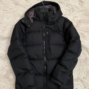 Svart dunjacka från Ralph Lauren - Svart Polo Ralph Lauren Jacka i bra skick men den har två slitningar på vardera arm. Men det är lätt att laga då man bara kan sätta en liten lagning på hålen.