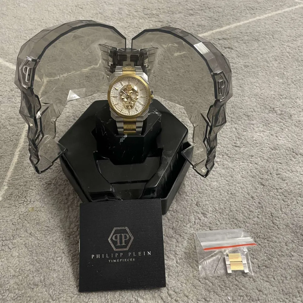 Snygg Philipp Plein herrklocka med en iögonfallande design. Klockan har en tvåfärgad länkarmband i silver och guld samt en detaljerad urtavla. Perfekt för den som vill sticka ut med stil.. Asusteet.
