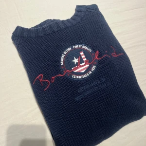 Mörkblå stickad tröja från Bondelid - Säljer en snygg mörkblå stickad tröja från Bondelid med ett coolt tryck på bröstet. Tröjan har långa ärmar och ribbade kanter vid hals, ärmslut och nederkant. Perfekt för kyligare dagar! Pris kan diskuteras 