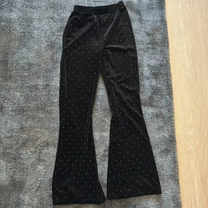 Svarta byxor med glittrigt mönster - Snygga svarta byxor med glittrigt mönster som är ett sett med linnet. De har en låg midja och en bootcut-stil som ger en trendig look. Perfekta för att lägga till lite glamour till din outfit.