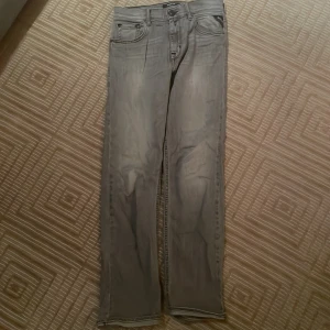 Grå jeans från Replay - Snygga grå jeans från Replay med klassisk femficksdesign. De har en rak passform och är perfekta för en avslappnad stil. Märkeslogga på baksidan ger en extra touch.