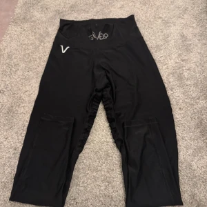 Svarta träningsbyxor från Gavelo - Snygga svarta träningsbyxor från Gavelo med hög midja och ribbade detaljer längs sidorna. Perfekta för gymmet eller yoga. Byxorna har en tight passform och är tillverkade i ett stretchigt material för bästa komfort.