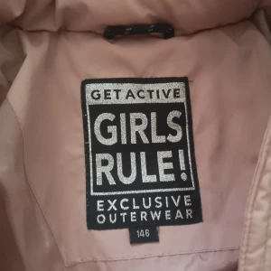 Rosa dunjacka från Girls Rule - Säljer en snygg rosa dunjacka från Girls Rule. Jackan har en hög krage och dragkedja framtill. Perfekt för kalla dagar med sin quiltade design och långa ärmar.