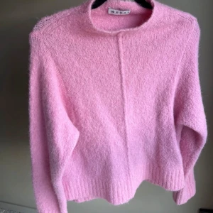 Stickad Rosa tröja från Wera - Mysig rosa tröja från Wera i en mjuk alpackablandning. Perfekt för kyliga dagar med sin fluffiga textur och långa ärmar. En stilren och bekväm tröja för alla tillfällen. 