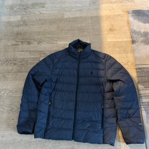 Mörkblå quiltad jacka från Ralph Lauren - Säljer en snygg mörkblå quiltad jacka från Ralph Lauren. Jackan har en dragkedja framtill och långa ärmar. Perfekt för kyligare dagar.