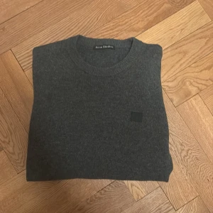 Acne Studios Stickad Tröja - Mörkgrå stickad tröja från Acne Studios, Stl S. Inga defekter, perfekt skick! Gjord i 100% ull. Tröjan har gråa armbågslappar i mocka. Hör av dig vid frågor eller funderingar!