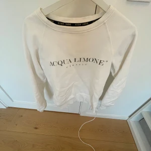 Vit tröja från Acqua Limone - Säljer en vit tröja från Acqua Limone med tryck fram och ett stort citronmotiv på baksidan. Tröjan har långa ärmar och en rund halsringning. Perfekt för en avslappnad stil. Den är perfekt för sommaren och perfekt till att ha på sig när som helst! Köpt på en butik i fjällbacka i somras! Men inte fått så mycket användning av den! Säljer då jag inte använder den! Köpt för 800 men säljer för 300! Skriv för frågor eller funderingar ❤️🙌
