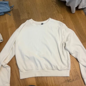 Vit ribbad tröja - Säljer en stilren vit ribbad tröja med långa ärmar. Perfekt för en avslappnad look. Tröjan har en rund halsringning och är gjord i ett mjukt material.