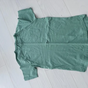 Grön t-shirt med bröstficka - Säljer en gröb T-shirt som funkar till både barn men oxå om du bär storlek xs, så fin grön färg. Passar super fint till blå jeans!!