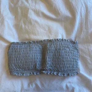 Grå bandeau bikiniöverdel - Snygg grå bandeau bikiniöverdel med smockad design. Perfekt för soliga dagar vid stranden eller poolen. Enkel och stilren utan axelband.