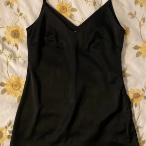 Svart klänning från Nasty Gal - Snygg svart klänning från Nasty Gal med v-ringning och smala axelband. Perfekt för en stilren look. Klänningen har en dragkedja på sidan för enkel påklädning.