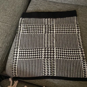 Rutig kjol i svart och vit - Snygg rutig kjol i svart och vit med ett klassiskt mönster. Kjolen har en tight passform och är perfekt för att ge en stilren look. Den är i stickat material och bekvämt material som passar bra till olika tillfällen.