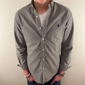 Grå Ralph Lauren skjorta  - Nu säljer vi ännu en fet polo skjorta som passar till alla tillställningar, skjortan är i mycket bra skick och du får den till ett rimligare pris för att kunna utrycka din stil utan att det blir för dyrt!🕺🍾💼🤩  Storlek👔: M Nypris💰: ca 1499 kr