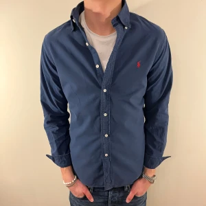 Blå Ralph Lauren skjorta - Nu säljer vi ännu en fet polo skjorta som passar till alla tillställningar, skjortan är i bra skick men är urtvättad och blekningar finns på ärmen(se sista bilden) samt är urtvättad vid sömmarna men inget man tänker på! (Vi sänker priset mycket pga detta)! Du ska kunna utrycka din stil utan att det blir för dyrt!🕺🍾💼🤩  Storlek👔: M Nypris💰: ca 1499 kr