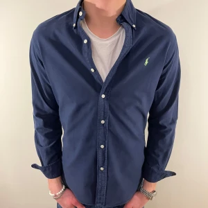 Mörkblå Ralph Lauren skjorta - Nu säljer vi ännu en fet polo skjorta som passar till alla tillställningar, skjortan är i mycket bra skick men har tyvärr ytterst litet hål på ena ärmen vilket syns på sista bilden! (Vi sänker priset mycket pga detta)! Du ska kunna utrycka din stil utan att det blir för dyrt!🕺🍾💼🤩  Storlek👔: M Nypris💰: ca 1499 kr