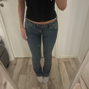 Blå lågmidjade bootcut jeans - Säljer ett par snygga blå lågmidjade bootcut jeans från Zara i storlek XS/34. De har en klassisk design med fem fickor och en knappgylf. Perfekta för en casual look.