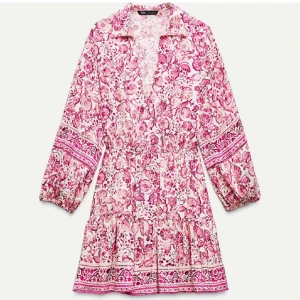 Mönstrad rosa Zara klänning - Populär Zara klänning med blommigt mönster och långa ärmar. Klänningen har en v-ringad design och volangdetaljer vid fållen. Perfekt för vår och sommar.