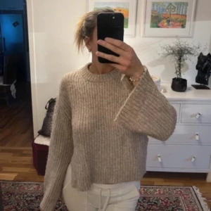 Beige stickad tröja - Säljer en mysig beige stickad tröja med långa ärmar och ribbad design. Perfekt för kyliga dagar och enkel att matcha med olika outfits.