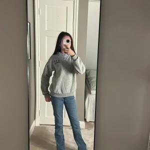 Grå hoodie med text - Säljer en grå hoodie med texten 'JE M'EN AMOUR' och en stjärna tryckt på framsidan. Hoodien har en klassisk passform med långa ärmar och en bekväm huva. Perfekt för en avslappnad stil.💕