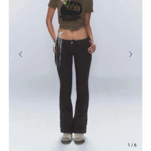 Svarta bootcut jeans - Snygga svarta bootcut jeans med låg midja och en tight passform upptill. Jeansen har en klassisk femficksdesign och en subtil broderad detalj i rosa på bakfickan. Perfekta för en trendig look. Jeansen är helt nya