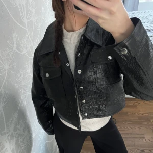 Skinnjacka - Snygg svart croppad skinnjacka från Missguided med krokodilpräglat mönster. Jackan har silverfärgade knappar och två bröstfickor med lock. Aldrig använd💕