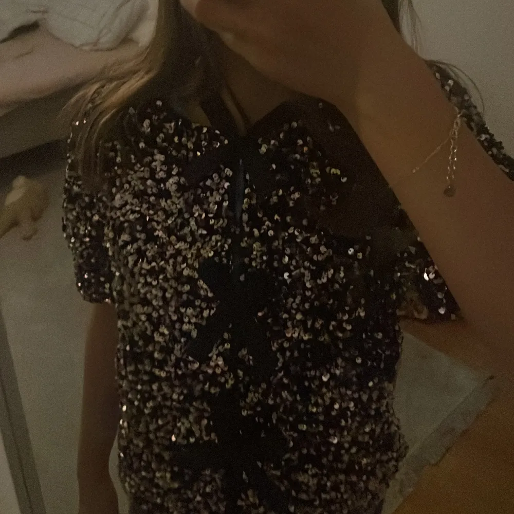 Snygg svart paljettopp med korta ärmar och rosetter framtill. Jätte fin och passar till det mesta. Från gina young, aldrig använd. Pris går att diskutera. Yläosat.