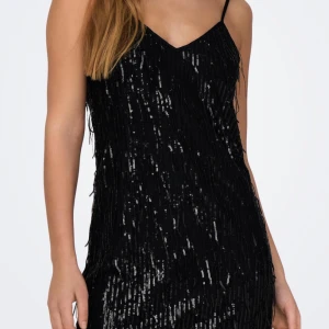 Svart paljettklänning - Snygg svart klänning med paljetter och smala axelband. Perfekt för en glittrig kväll med v-ringad design som ger en elegant touch. Aldrig använd❤️